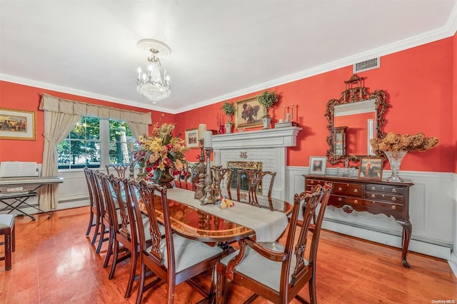 dining room with a chandelier, hardwood / wood-style floors, a baseboard radiator, and ornamental molding