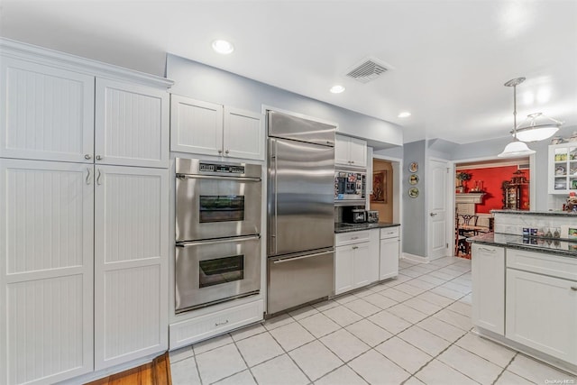 kitchen featuring light tile patterned floors, built in appliances, and white cabinetry