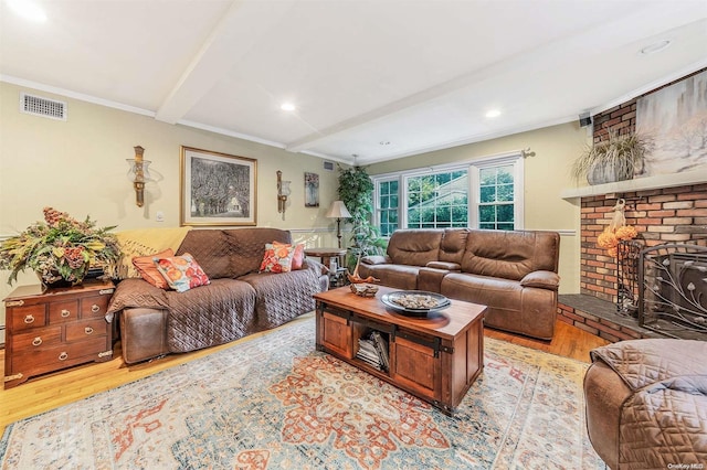 living room with a fireplace, beam ceiling, light hardwood / wood-style floors, and crown molding