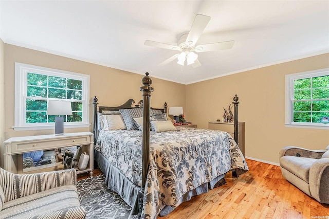 bedroom featuring multiple windows, ceiling fan, hardwood / wood-style floors, and ornamental molding