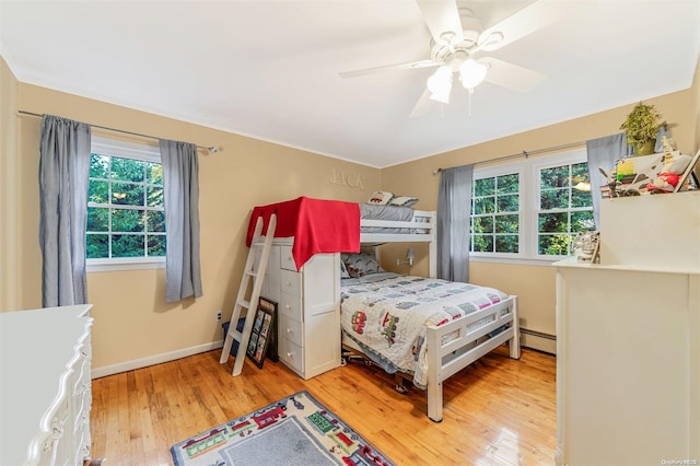 bedroom featuring multiple windows, ceiling fan, hardwood / wood-style floors, and a baseboard radiator