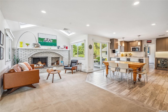 living room with a fireplace, vaulted ceiling, light hardwood / wood-style flooring, and beverage cooler