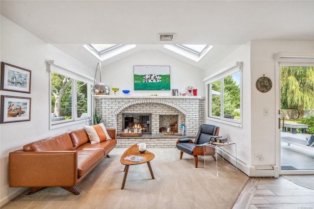 interior space featuring light wood-type flooring, lofted ceiling with skylight, and a fireplace