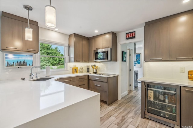 kitchen with light wood-type flooring, backsplash, sink, wine cooler, and hanging light fixtures