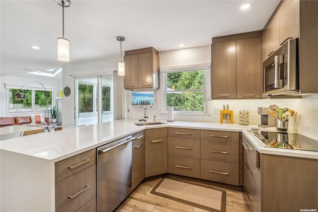 kitchen with decorative light fixtures, plenty of natural light, light wood-type flooring, and appliances with stainless steel finishes