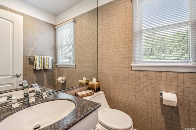 bathroom with vanity, toilet, and tile walls