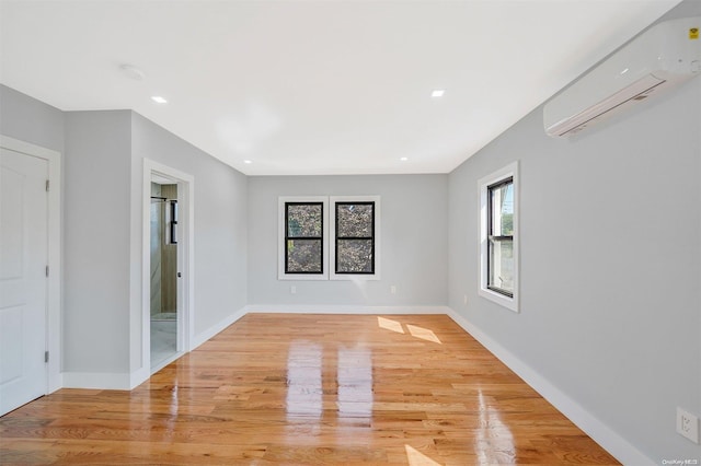 unfurnished room featuring an AC wall unit and light wood-type flooring