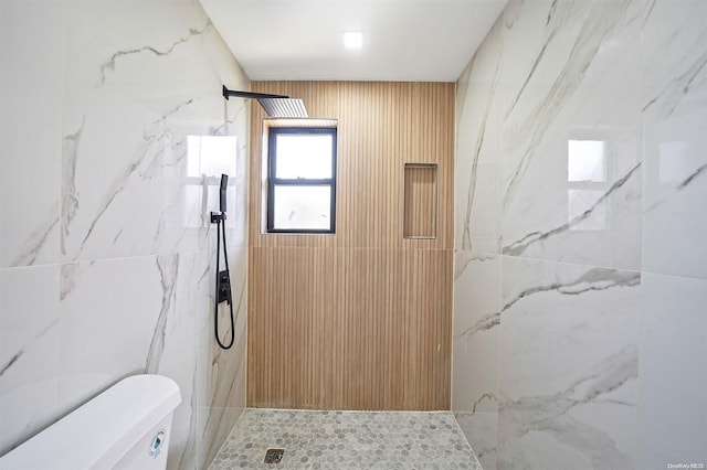 bathroom featuring tiled shower and toilet