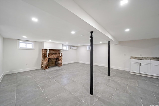 basement with a healthy amount of sunlight, a wall mounted air conditioner, sink, and a brick fireplace