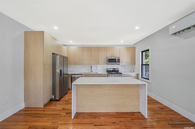 kitchen with sink, light hardwood / wood-style flooring, appliances with stainless steel finishes, a kitchen island, and a wall unit AC