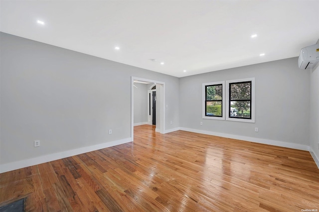 spare room with light hardwood / wood-style flooring and an AC wall unit