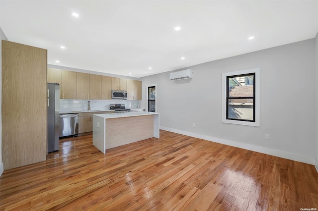 kitchen featuring a center island, a wall unit AC, stainless steel appliances, light hardwood / wood-style floors, and decorative backsplash