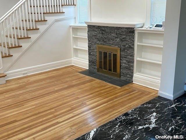 living room featuring hardwood / wood-style flooring, built in features, and a fireplace