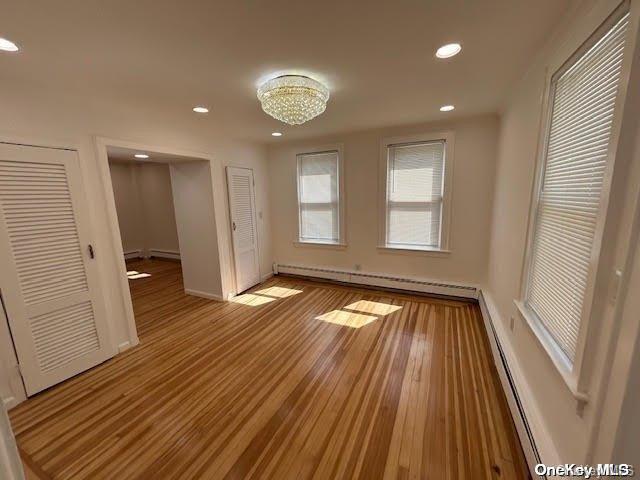 interior space with an inviting chandelier, light hardwood / wood-style floors, and a baseboard heating unit