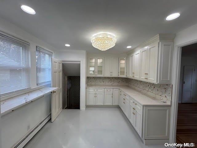 kitchen with decorative backsplash, white cabinetry, and a baseboard radiator