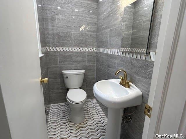 bathroom featuring toilet and tile walls