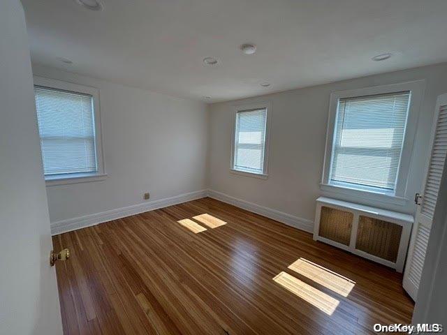 empty room with dark wood-type flooring and radiator