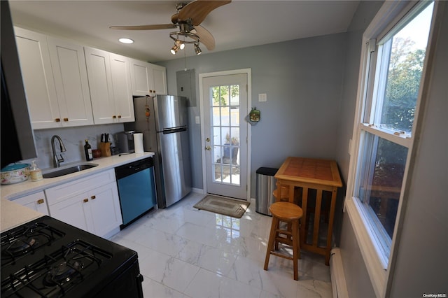 kitchen featuring white cabinets, appliances with stainless steel finishes, a baseboard radiator, and sink