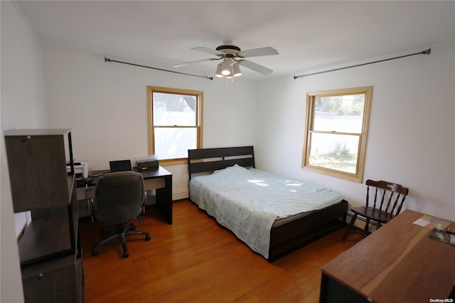 bedroom featuring baseboard heating, ceiling fan, and wood-type flooring