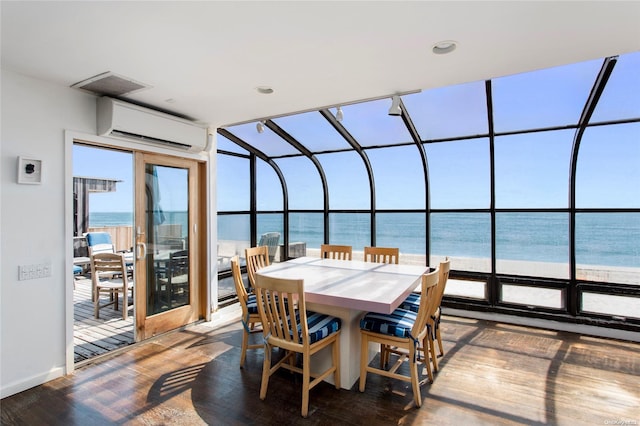 interior space with a beach view, a water view, and an AC wall unit