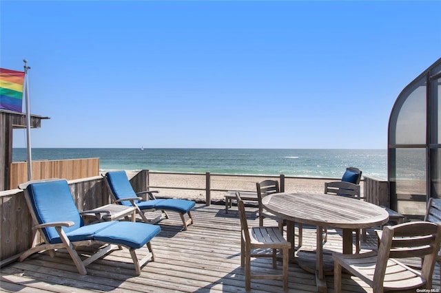 wooden terrace featuring a water view and a view of the beach