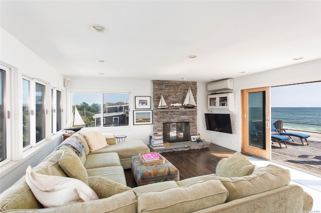 living room featuring a wall mounted air conditioner, hardwood / wood-style floors, a water view, and a fireplace