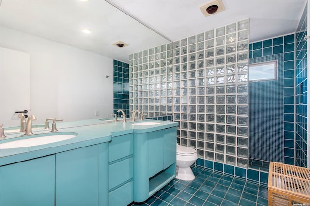 bathroom with vanity, tile patterned floors, toilet, tile walls, and a tile shower