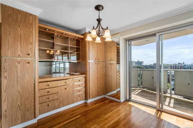 unfurnished dining area featuring crown molding, an inviting chandelier, and hardwood / wood-style flooring