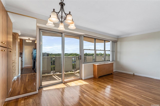 spare room featuring light wood-type flooring, crown molding, and an inviting chandelier