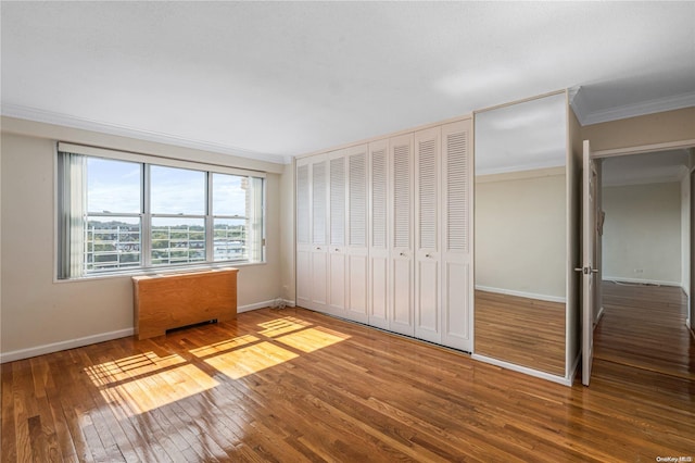 unfurnished bedroom featuring hardwood / wood-style floors, a closet, and ornamental molding