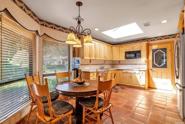 dining room featuring light tile patterned floors, a skylight, an inviting chandelier, and sink