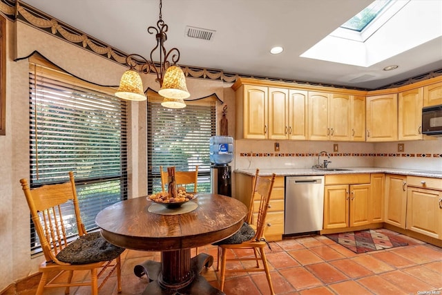 kitchen featuring a skylight, dishwasher, light brown cabinets, sink, and pendant lighting