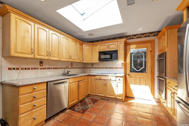 kitchen featuring a skylight, decorative backsplash, sink, and stainless steel appliances