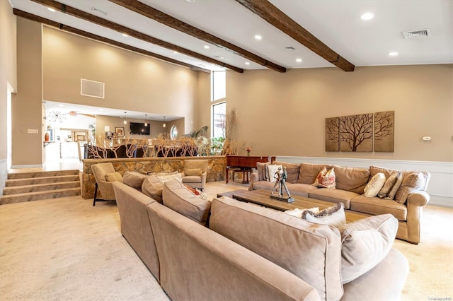 carpeted living room featuring beamed ceiling and a towering ceiling