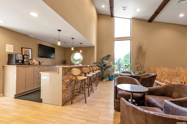 bar with pendant lighting, plenty of natural light, beam ceiling, and a towering ceiling