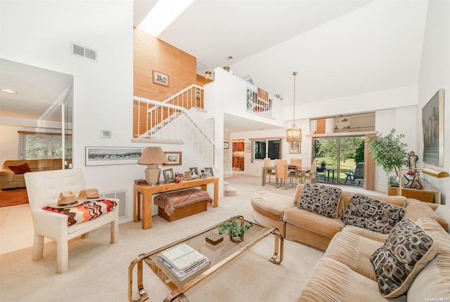 carpeted living room with a notable chandelier and high vaulted ceiling