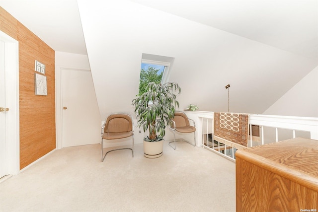 sitting room with carpet, vaulted ceiling, and wood walls