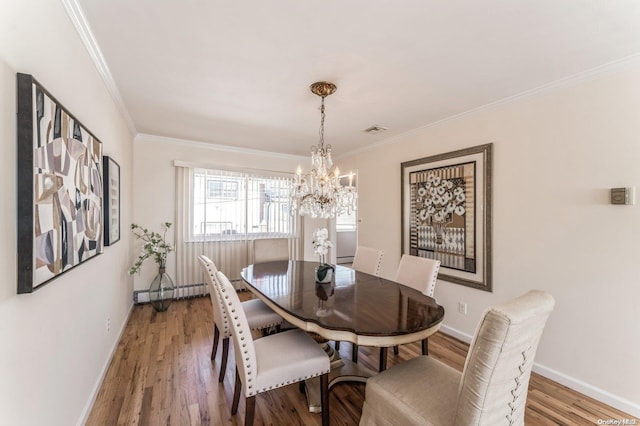 dining space with hardwood / wood-style floors, ornamental molding, and a chandelier