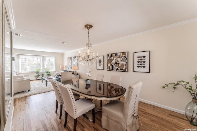 dining space featuring hardwood / wood-style flooring, crown molding, and a notable chandelier