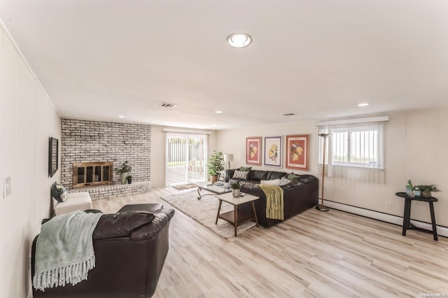 living room featuring a fireplace, a baseboard radiator, and light wood-type flooring