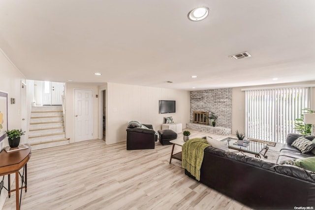 living room with a fireplace and light wood-type flooring