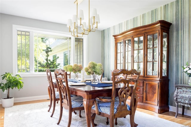 dining area with light wood-type flooring and a notable chandelier