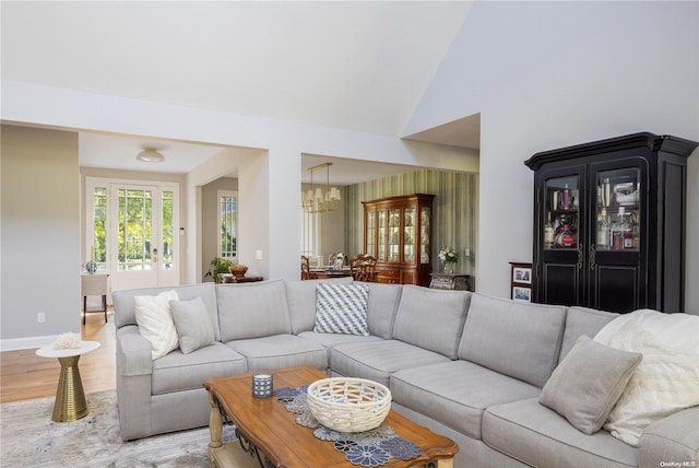 living room with high vaulted ceiling, wood-type flooring, and a notable chandelier