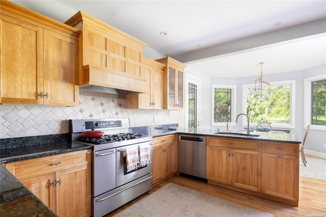 kitchen with backsplash, stainless steel appliances, sink, light hardwood / wood-style flooring, and dark stone countertops