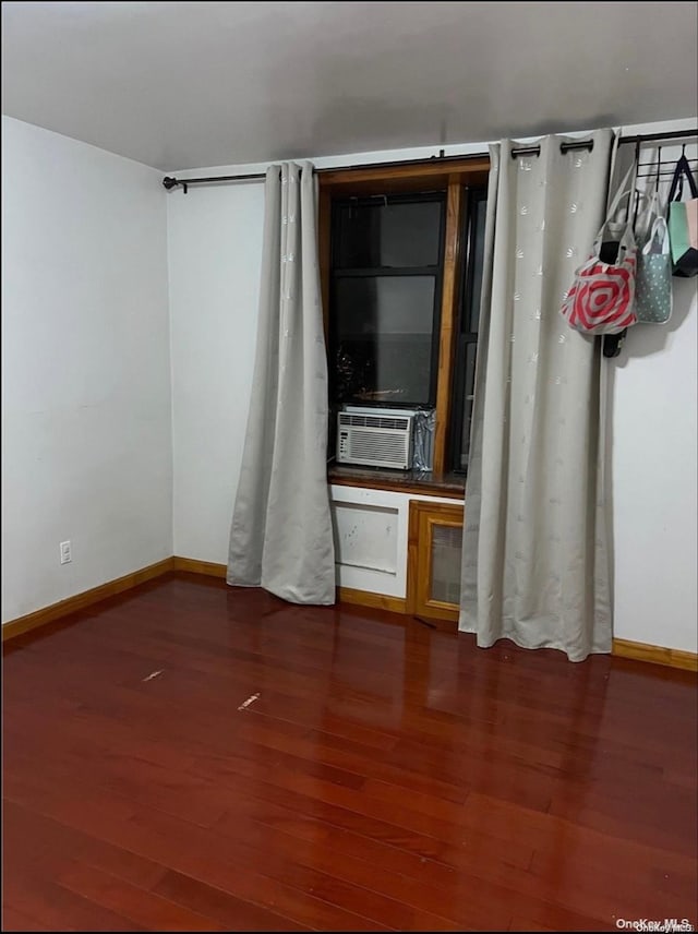 spare room featuring cooling unit and dark wood-type flooring