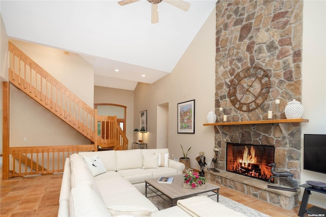 living room with ceiling fan, a stone fireplace, and high vaulted ceiling