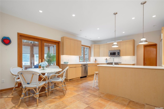 kitchen featuring backsplash, sink, hanging light fixtures, light brown cabinetry, and appliances with stainless steel finishes