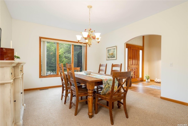 carpeted dining area with an inviting chandelier