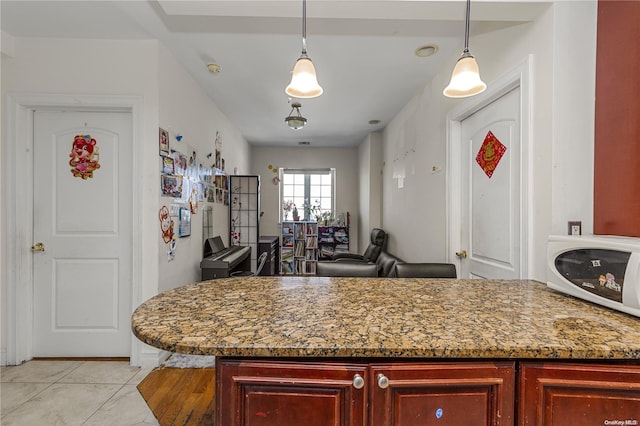 kitchen featuring light tile patterned floors, hanging light fixtures, and dark stone counters