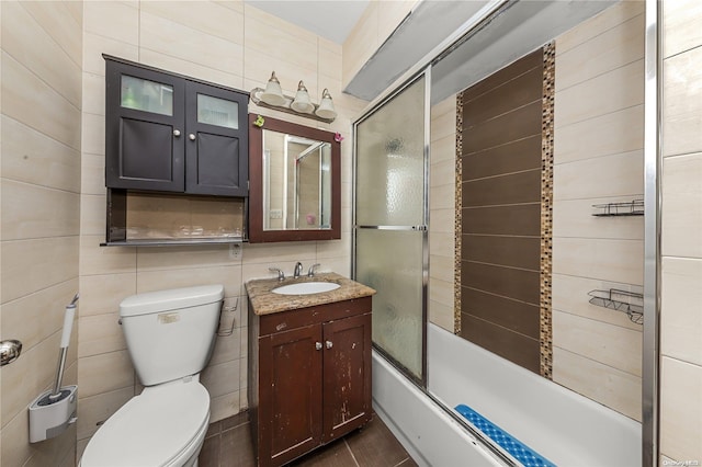 full bathroom with toilet, vanity, tile walls, and combined bath / shower with glass door